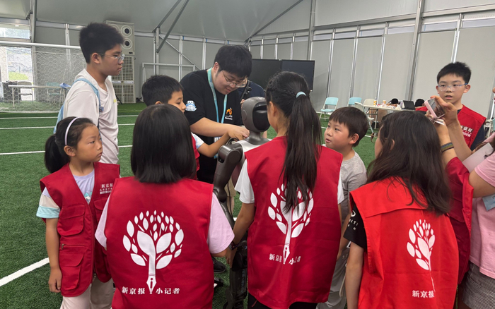 清华大学自动化系本科生郭砼（中）和孩子们介绍了踢球机器人。 新京报记者米潇楠 摄